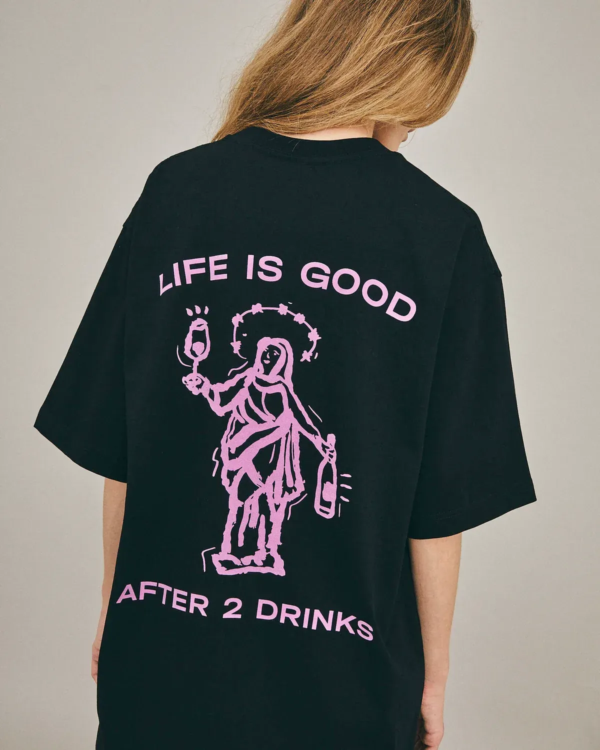 Спина чёрной футболки с розовым принтом и надписью life is good after 2 drinks